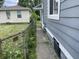 Side yard featuring a chain link fence, overgrown foliage, and a cement walkway at 3636 Crescent Ave, Indianapolis, IN 46208