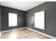 Bedroom featuring gray walls, light hardwood floors, and two bright windows at 3636 Crescent Ave, Indianapolis, IN 46208