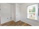 A small bedroom with wood floors, a window with blinds, white walls, and a door at 3636 Crescent Ave, Indianapolis, IN 46208