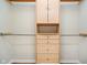 This closet features wood-colored built-in organizers, cabinets, drawers, and hanging rods for optimal storage at 5240 Ochs Ave, Indianapolis, IN 46254