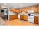 Well-lit kitchen featuring wood cabinets, granite countertops, and modern white appliances at 5253 W 8Th Street Rd, Anderson, IN 46011