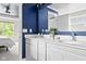 This bathroom has white cabinets, double sinks, a blue wall, and a mirror view into another room at 5264 Veranda Dr, Noblesville, IN 46062