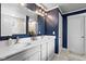 Elegant bathroom showcasing double sinks, white cabinets, modern lighting, blue walls, and large mirror at 5264 Veranda Dr, Noblesville, IN 46062