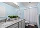 Bright bathroom with granite countertop, dual sinks, and blue striped shower curtain at 5264 Veranda Dr, Noblesville, IN 46062