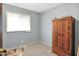 Carpeted bedroom showcasing a window, a vintage armoire, and neutral-colored walls at 5349 Culver St, Indianapolis, IN 46226
