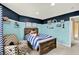 Charming bedroom with blue accent wall, rustic wooden bed frame, and a view to the hallway at 5598 W Woodstock Trl, McCordsville, IN 46055