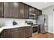 Close up of kitchen with stainless steel appliances and dark wood cabinets at 5598 W Woodstock Trl, McCordsville, IN 46055