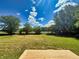 Expansive backyard featuring a wooden deck, lush green grass, mature trees, and a serene rural setting under a sunny sky at 5861 N 330 W, Columbus, IN 47201
