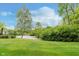Well-manicured lawn leading to a serene pond surrounded by mature trees and lush greenery, enhancing its appeal at 5939 Oberlies Way, Plainfield, IN 46168