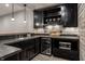 Basement bar with black cabinets, mosaic tile backsplash, mini fridge, and microwave at 6639 E Deerfield Dr, Zionsville, IN 46077