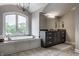 Bright bathroom features a large tub under a window and a vanity with dark cabinets at 6639 E Deerfield Dr, Zionsville, IN 46077