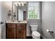 Bathroom with wood vanity, marble top, toilet, and window letting in natural light at 6639 E Deerfield Dr, Zionsville, IN 46077