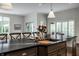 Kitchen island with black countertops, double sink, barstool seating, and modern pendant lights at 6639 E Deerfield Dr, Zionsville, IN 46077