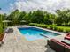 Inviting backyard pool with lounge chairs, umbrellas, and a patio surrounded by lush greenery and manicured landscaping at 6639 E Deerfield Dr, Zionsville, IN 46077