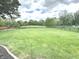Large backyard with a view of a pond, basketball court, bordered by a black metal fence at 7823 Ashtree Dr, Indianapolis, IN 46259