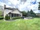 Spacious backyard featuring a well-maintained lawn, screened porch, patio with fire pit, and mature trees at 7823 Ashtree Dr, Indianapolis, IN 46259