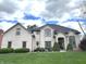 Beautifully landscaped white brick home with a lush green lawn, mature trees, and architectural details at 7823 Ashtree Dr, Indianapolis, IN 46259