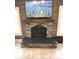 Close-up of the stone fireplace with wooden mantle and TV, flanked by windows with shutters at 7823 Ashtree Dr, Indianapolis, IN 46259