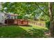 Backyard with a wooden deck, grill, firepit, and a tranquil pond with a decorative wooden fence at 8376 Glen Highlands Dr, Indianapolis, IN 46236