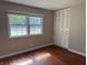 A bedroom with hardwood floors, a large window providing natural light, and a closet with shutter doors at 10328 Central Ave, Carmel, IN 46280