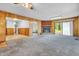 Carpeted living room enhanced by warm wood paneling, a brick fireplace, and abundant natural light at 10346 Wilson Rd, Brownsburg, IN 46112