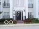 Inviting building entrance featuring well-maintained landscaping, black iron railings, and a charming overhead sign at 12860 University Cres # 1B, Carmel, IN 46032