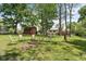 Outdoor fire pit area with chairs and table, framed by a well-maintained lawn, mature trees, and a charming red barn at 12920 N Oakhaven Dr, Camby, IN 46113