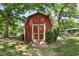 Exterior shot of a vintage red shed, complemented by neatly stacked wood and lush greenery, offering ample storage at 12920 N Oakhaven Dr, Camby, IN 46113