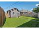 Back exterior view features a gray building, lush lawn, and wooden privacy fence at 1421 S New Jersey St, Indianapolis, IN 46225