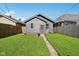 Back exterior view features a gray building, lush lawn, and wooden privacy fence at 1421 S New Jersey St, Indianapolis, IN 46225