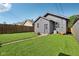 Back exterior view features a gray building, lush lawn, and wooden privacy fence at 1421 S New Jersey St, Indianapolis, IN 46225
