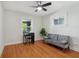 Sunlit bedroom with hardwood floors, a gray sofa, and a black desk at 1421 S New Jersey St, Indianapolis, IN 46225