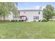 Spacious backyard with green grass, patio furniture with red umbrella, and mature trees, perfect for outdoor living at 14353 Chariots Whisper Dr, Carmel, IN 46074