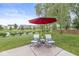 Backyard patio featuring an umbrella-covered table and chairs overlooking a tranquil pond at 14353 Chariots Whisper Dr, Carmel, IN 46074