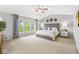 Bright main bedroom featuring a large bed, ceiling fan, and three windows with natural light at 14353 Chariots Whisper Dr, Carmel, IN 46074