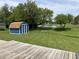 View of the expansive backyard featuring a small pond, lush trees, shed, and fire pit at 1562 Prairieview Ln, Greenfield, IN 46140