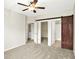 A spacious bedroom featuring neutral carpet, a ceiling fan, and a rustic sliding barn door at 2306 Brightwell Pl, Indianapolis, IN 46260