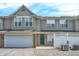 Inviting townhome features a one-car garage, green door, and charming white picket fence, creating a welcoming curb appeal at 2306 Brightwell Pl, Indianapolis, IN 46260