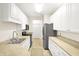 Efficient kitchen featuring white cabinetry, stainless appliances, and light-colored tile flooring at 2306 Brightwell Pl, Indianapolis, IN 46260