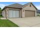 Close-up of the brick three-car garage with tan garage doors and concrete driveway at 2422 Oak Dr, Clayton, IN 46118