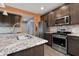 This upgraded kitchen features stainless appliances, dark cabinetry, tile backsplash, and granite countertops at 2502 Creekland Dr, Columbus, IN 47201