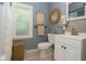 Stylish bathroom with blue walls, tile accents, a round mirror, and modern fixtures for a serene space at 3602 N Colorado Ave, Indianapolis, IN 46218