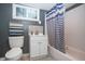 Updated bathroom features tiled floor, white vanity, toilet, and a shower-tub with blue striped curtain at 3602 N Colorado Ave, Indianapolis, IN 46218
