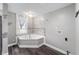 Bright bathroom featuring wood look flooring, a corner tub, and light-colored walls at 5312 E Southern Ave, Indianapolis, IN 46203
