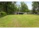 Charming one-story home with covered front porch, lush green lawn and mature trees surrounding the property at 5422 Orange St, Indianapolis, IN 46203