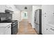 Kitchen with stainless steel appliances, white cabinets and countertops, and wood-look floors leading to hallway at 5422 Orange St, Indianapolis, IN 46203