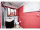 Bright bathroom featuring a single sink vanity, toilet, and shower with red walls at 5558 Bertha St, Indianapolis, IN 46241