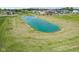 Aerial view of a serene pond surrounded by green grass and luxury homes in the background at 5790 Arcade Blvd, McCordsville, IN 46055