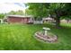 This back yard features lush grass, a bird bath, landscaping, and a red brick home at 5903 Schoolwood Dr, Speedway, IN 46224