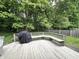 This back deck has a bench, grill, and is surrounded by mature trees and a green lawn at 6366 Stratford N Dr, Fishers, IN 46038